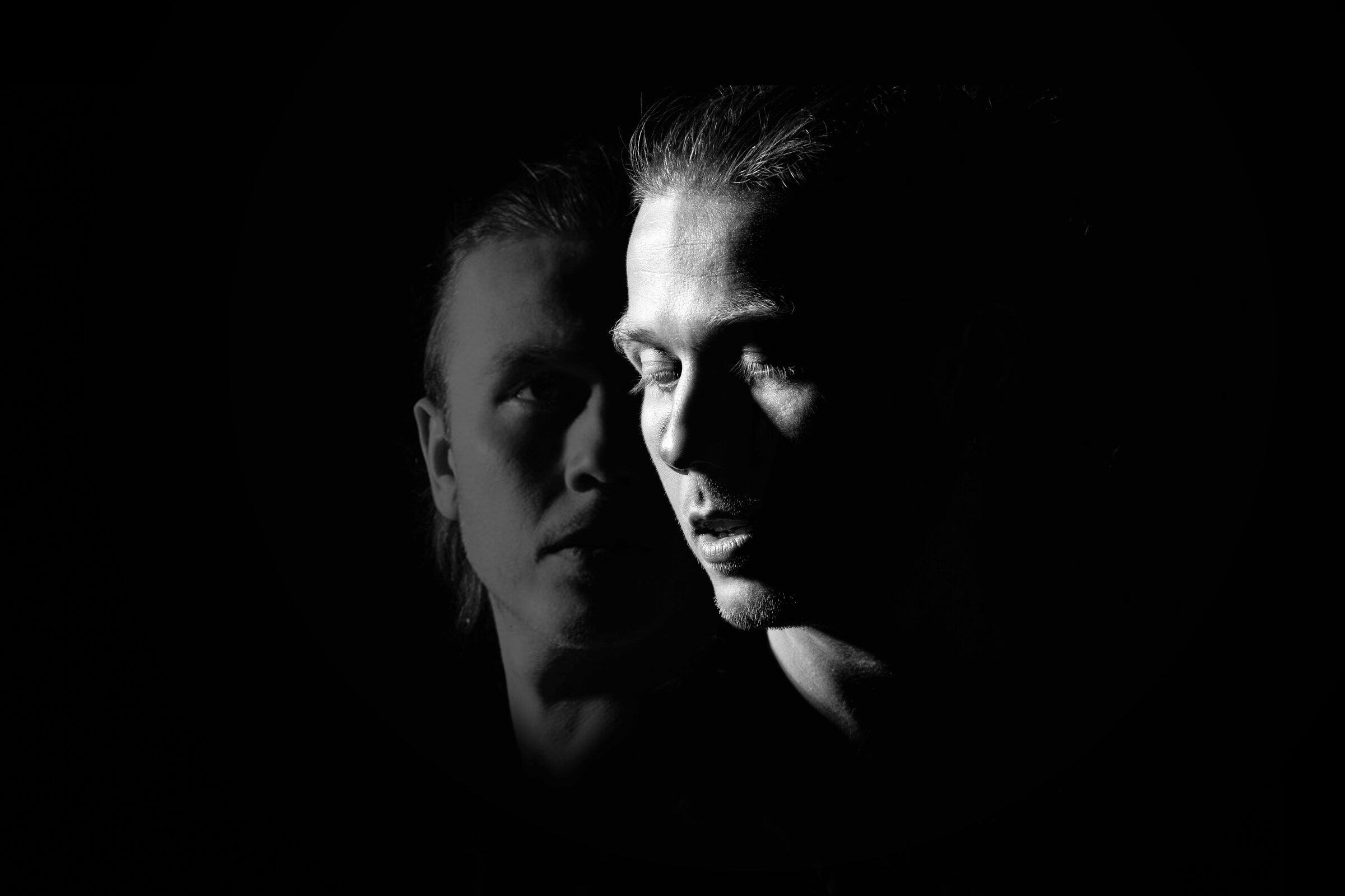 Two faces emerging from darkness — promotional image for the storytelling concert GLENN